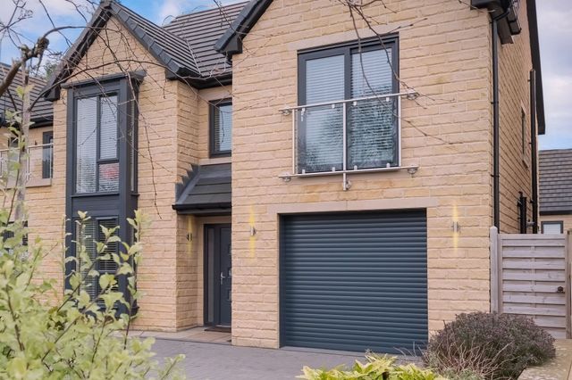 Beige brick townhouse style property with integral garage and garage door in dark grey matching door and window frames.