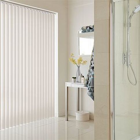 Canterbury cream coloured vertical blinds fitted to a tall and wide window in a bathroom decorated in white 