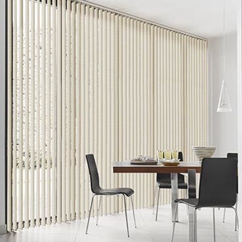 Beige coloured vertical blinds are fitted to a floor to ceiling window in a dining featuring a dining table and chairs while the room is decorated in white 