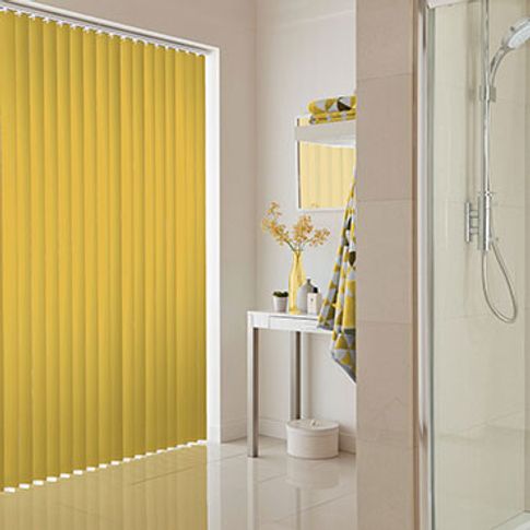 Yellow vertical blinds fitted to a wide rectangular window in a bathroom decorated in white tones
