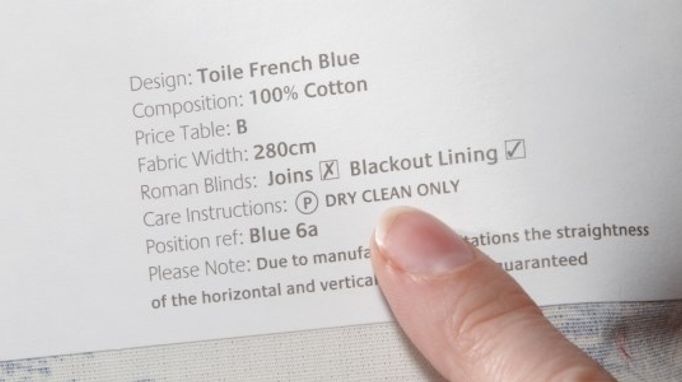 someone pointing the dry cleaning instructions on a piece of fabric